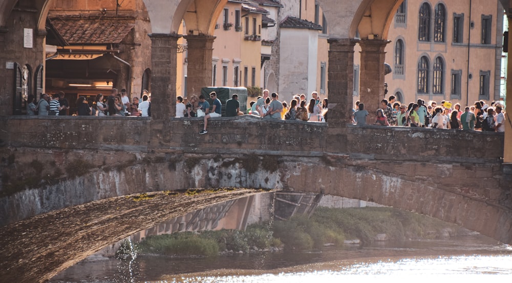 a group of people standing on a bridge over a river