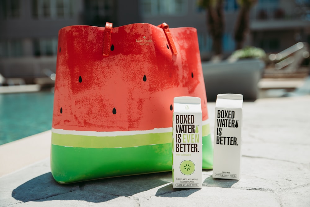 a watermelon bag sitting next to a bottle of water