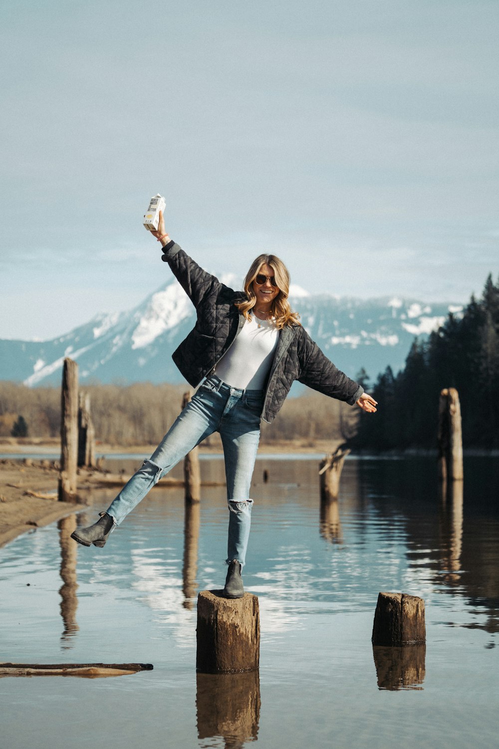 a woman standing on a log in the water