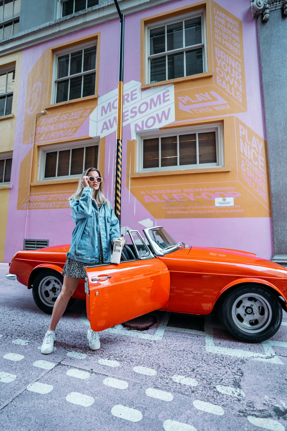 a woman standing next to an orange car