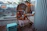 A cheerful mom relaxing on a budget-friendly outdoor lounge chair surrounded by string lights.