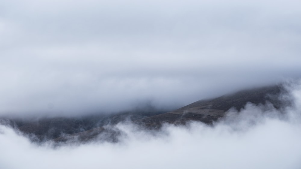 a mountain covered in fog and clouds on a cloudy day