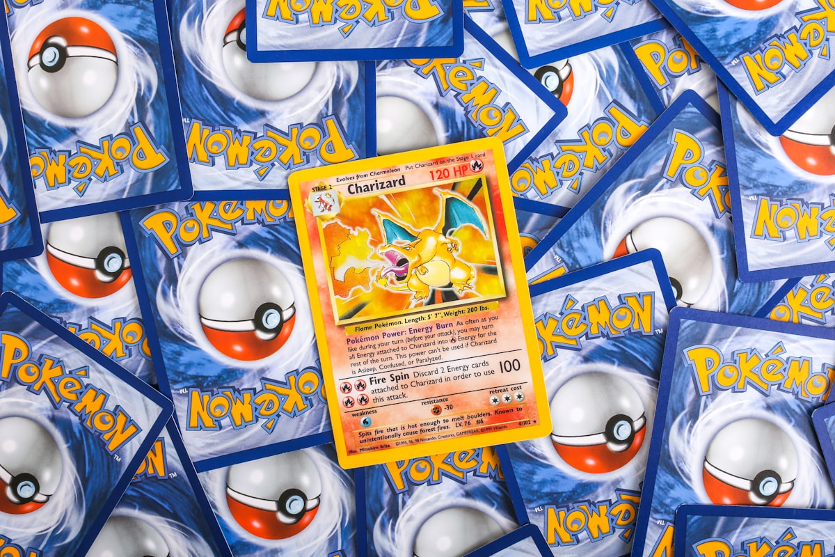 Veteran Pokemon TCG collector reviewing a binder stack of holographic cards on wooden desk during evening upgrade session