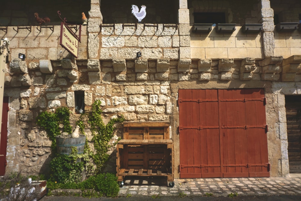 a brick building with a red door and a white bird flying over it