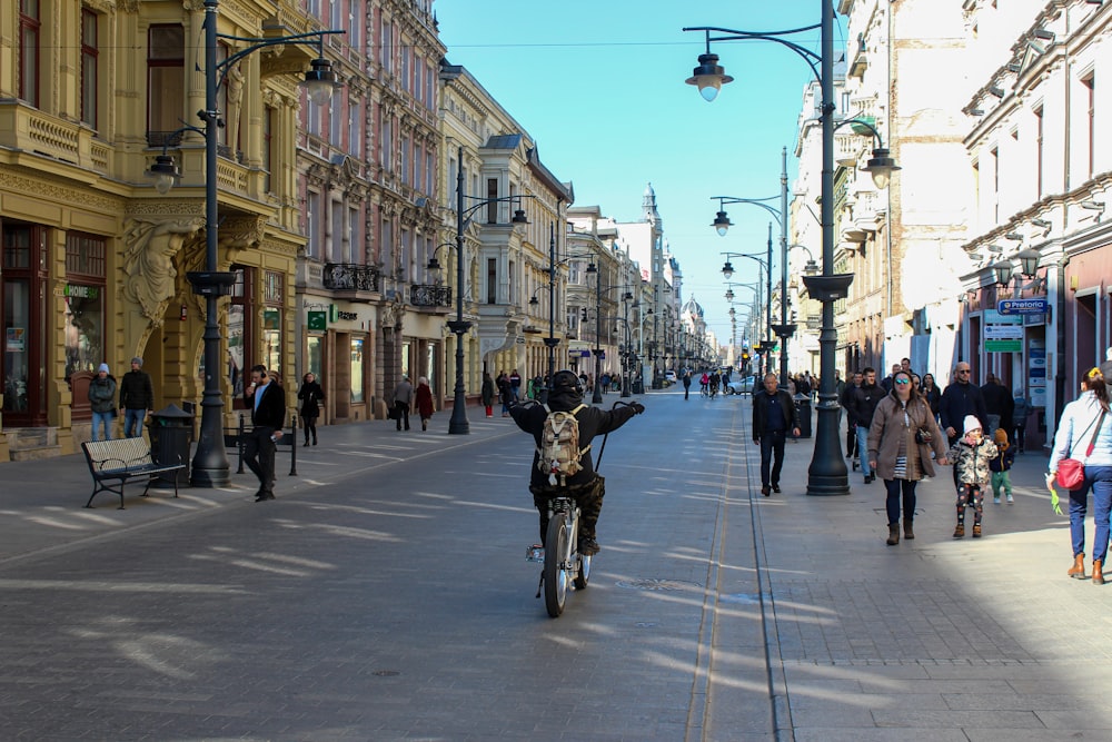 a man riding a bike down a street next to tall buildings