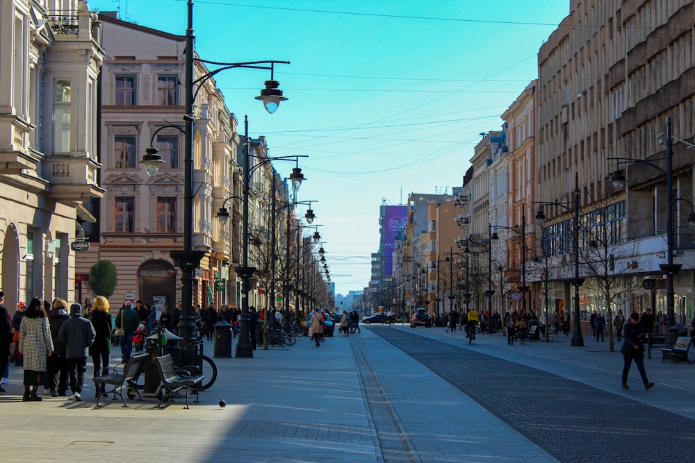 a group of people walking down a street next to tall buildings