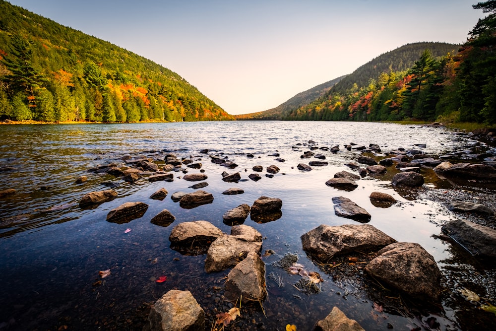 a lake surrounded by mountains and trees in the fall