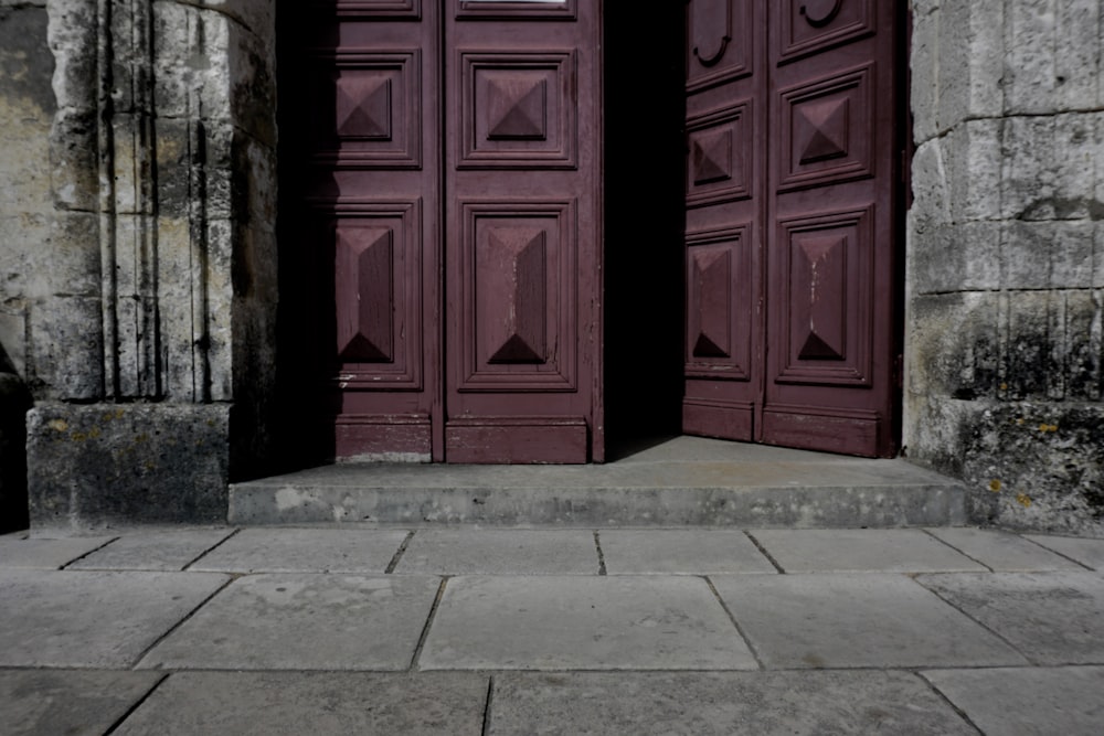 a black trash can sitting in front of a purple door