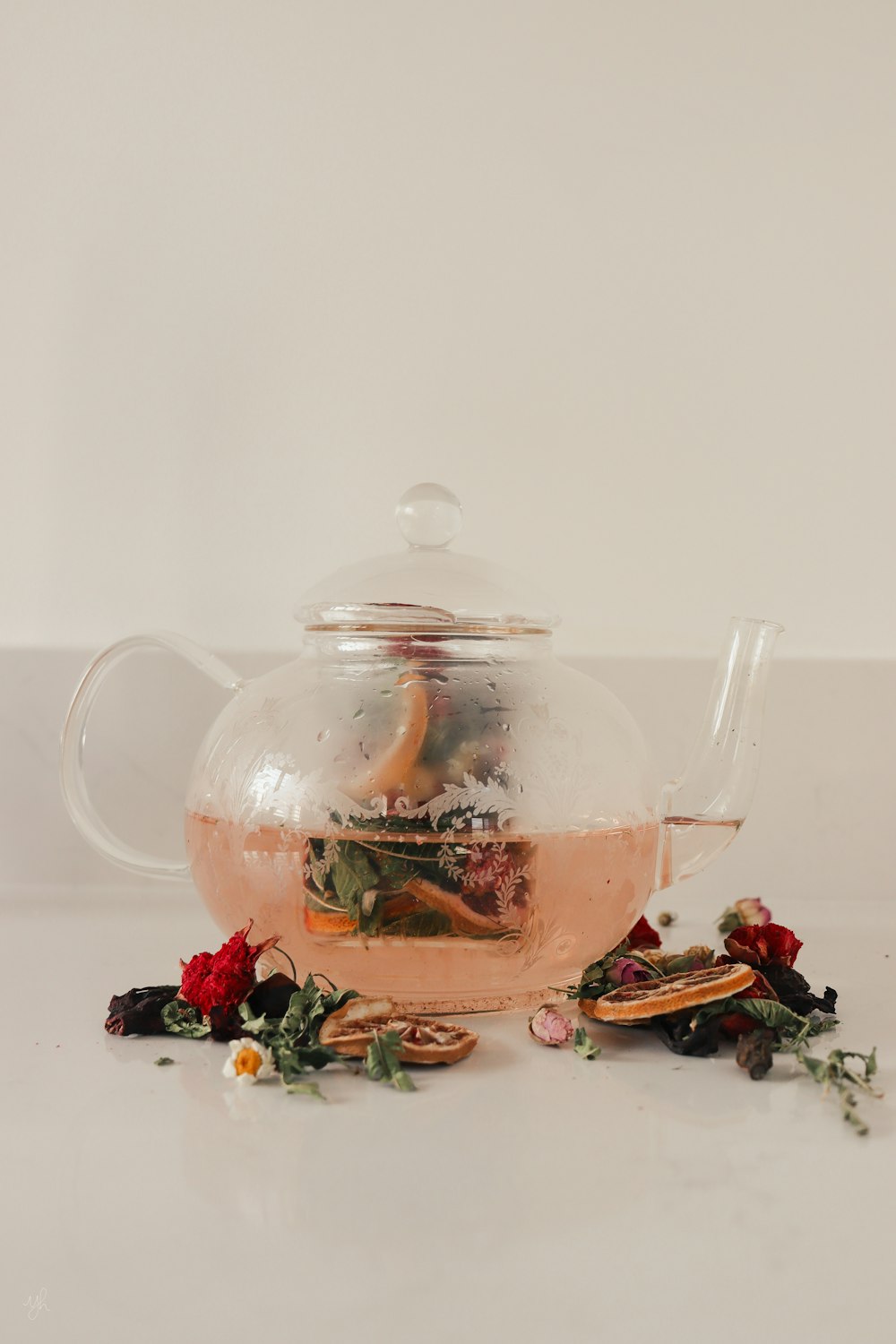 a glass tea pot filled with tea and flowers