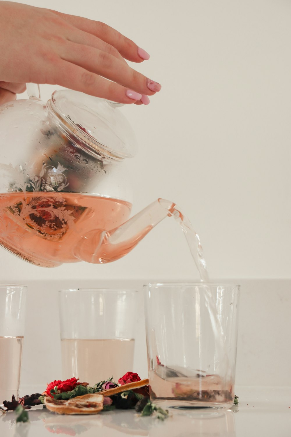 a person pouring tea into a glass teapot