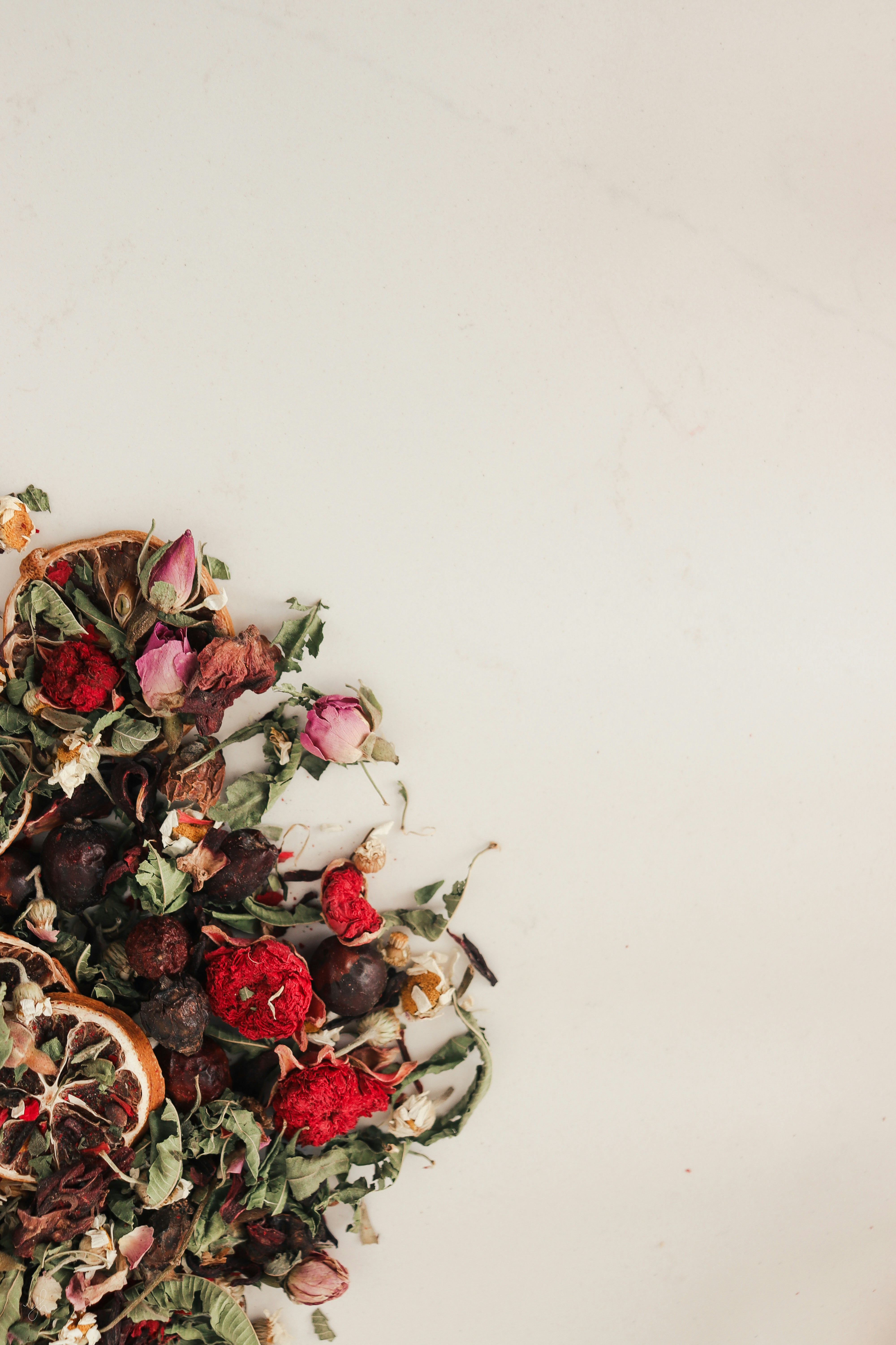 a pile of dried fruit and flowers on a white surface