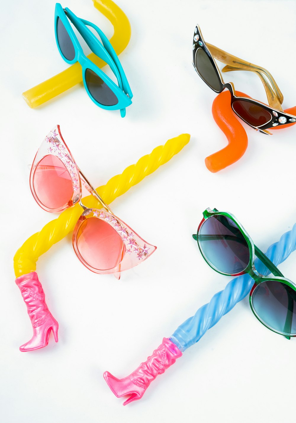 a group of four different colored sunglasses on a white surface