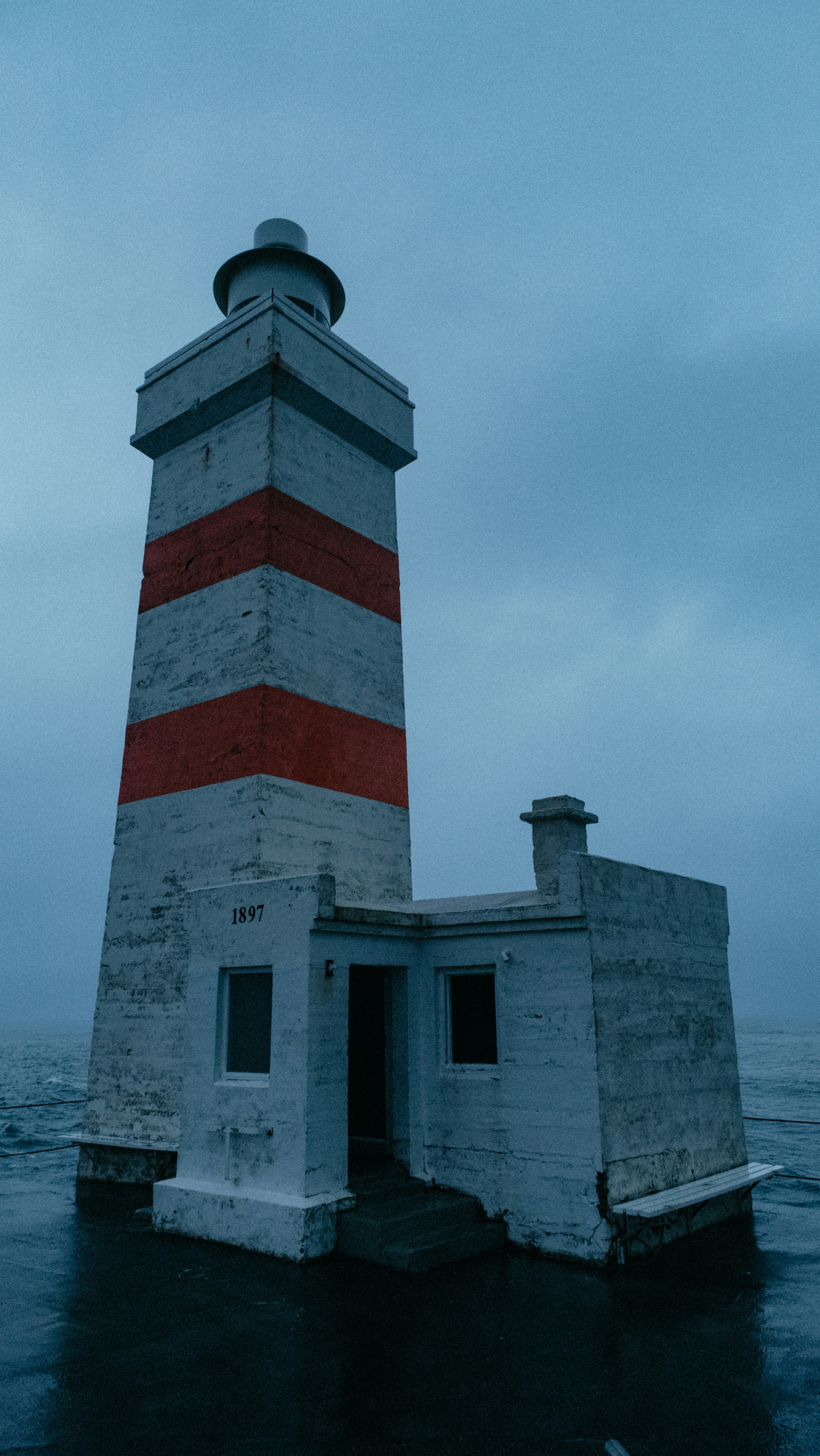 a red and white lighthouse sitting on top of a body of water