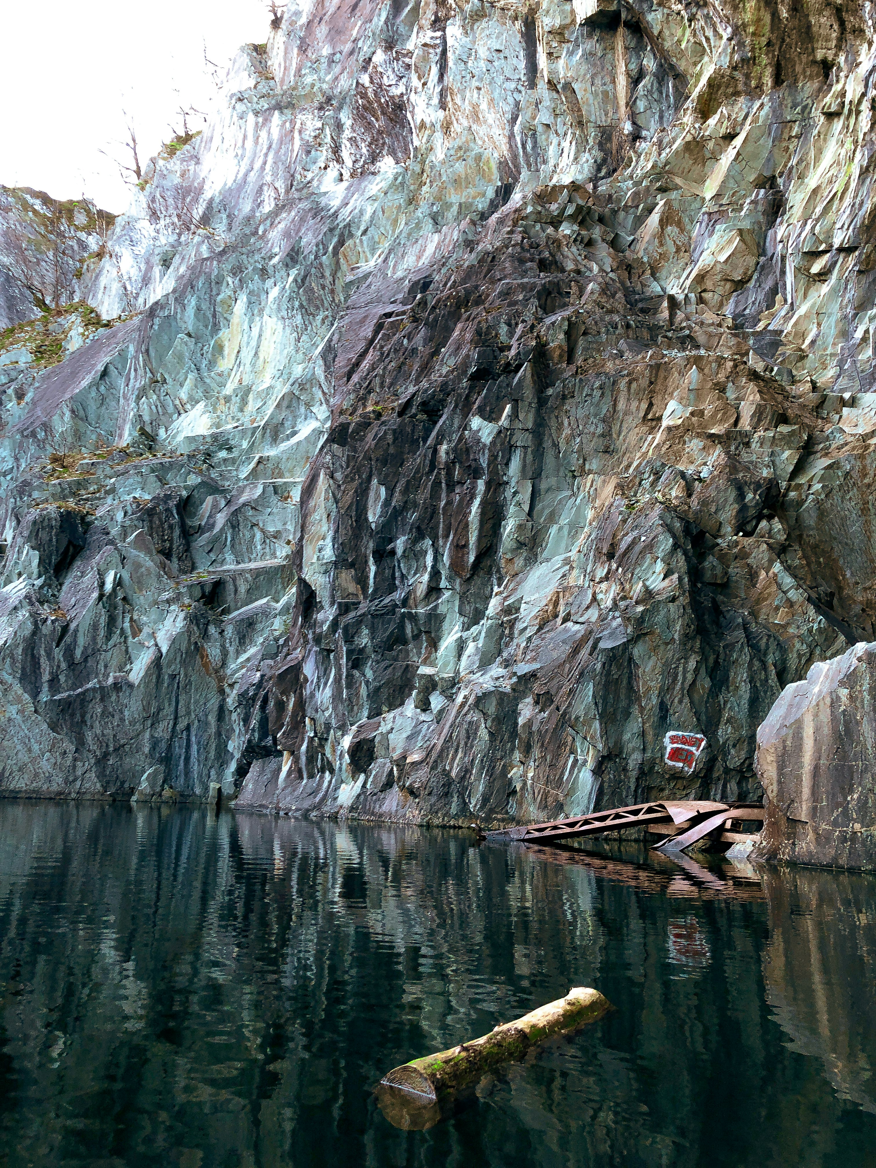 a body of water with a rock cliff in the background