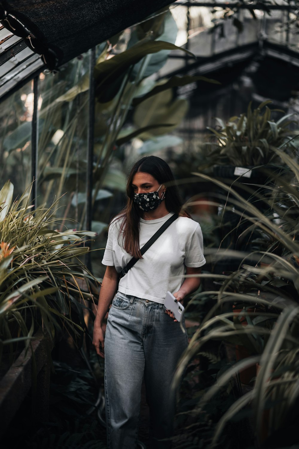 a woman wearing a mask standing in a greenhouse