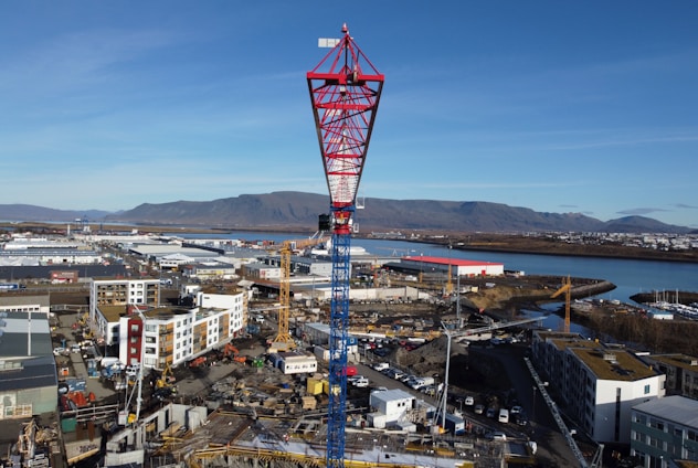Professional engineer reviewing blueprints at a construction site with cranes in the background.