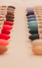 Rows of colorful crayon tips are arranged in parallel lines on a light background, with each crayon showing a variety of shades ranging from vibrant reds and pinks to calming blues and greens.