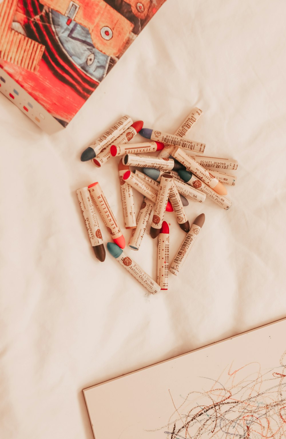 a pile of crayons sitting on top of a bed next to a book