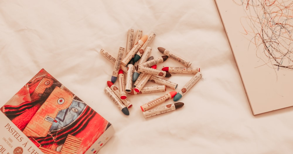 a pile of crayons sitting on top of a bed next to a book