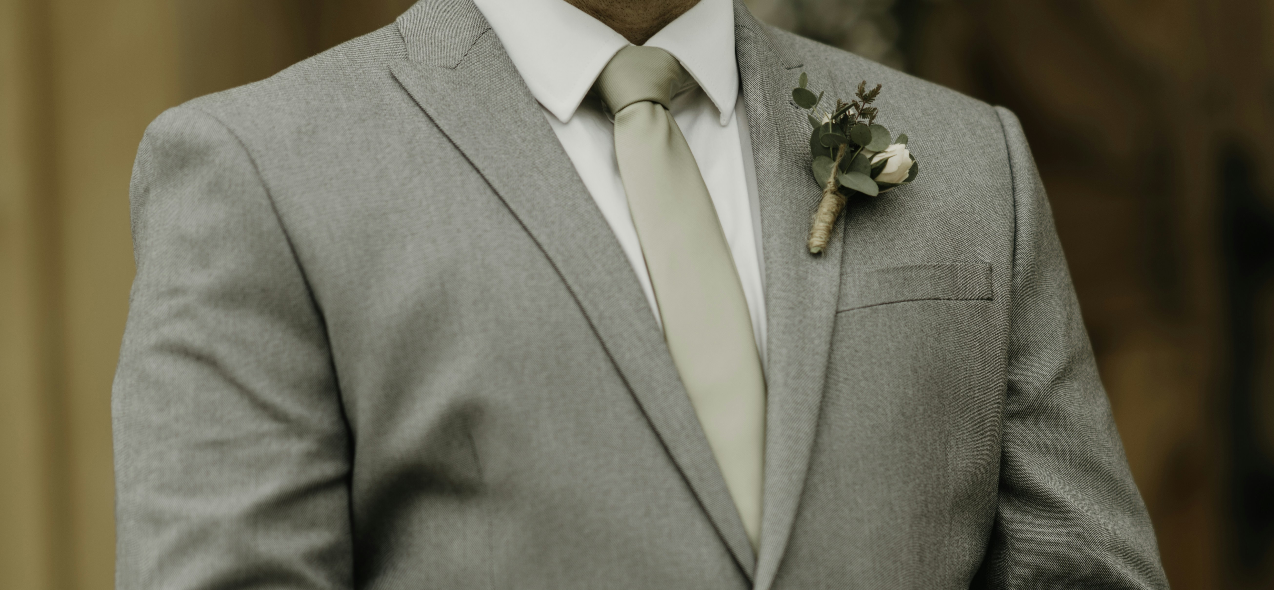 a man in a gray suit with a boutonniere on his lapel