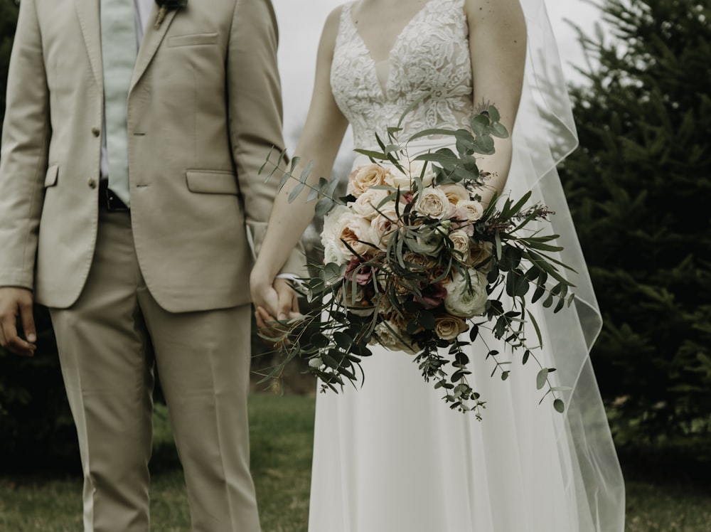 a bride and groom holding hands in a field