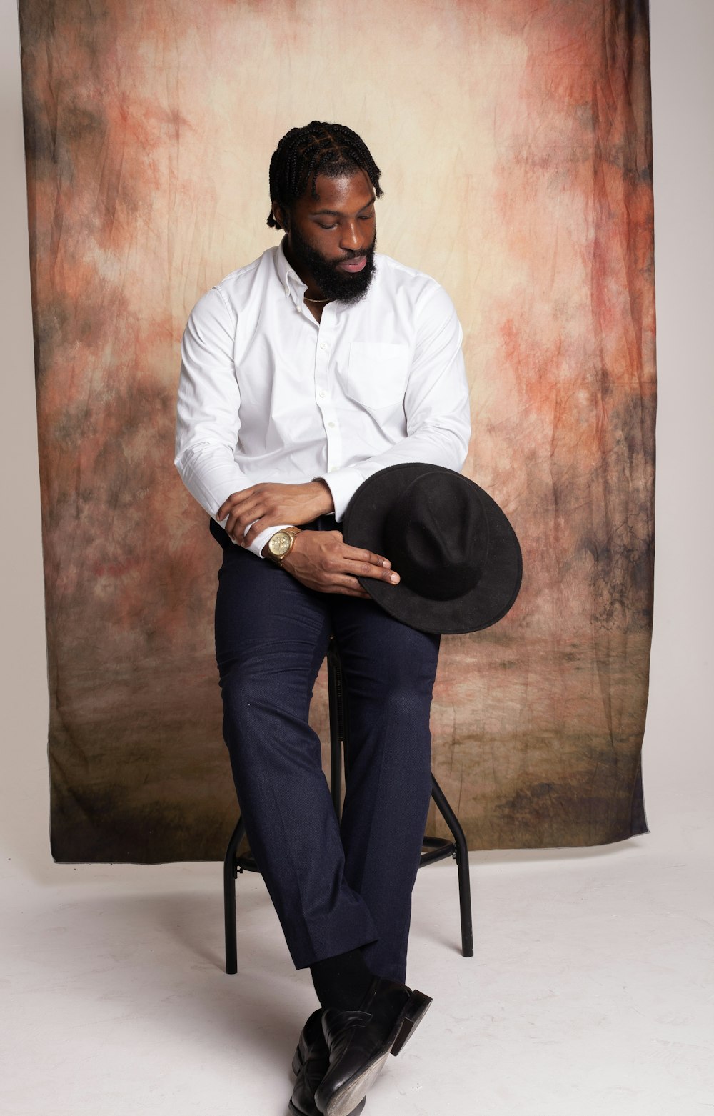 a man sitting on a chair wearing a hat