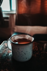 A warm ceramic mug with a playful design, filled with steaming coffee on a kitchen counter.