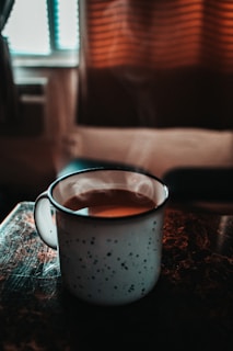 A cozy scene featuring a ceramic-style insulated mug filled with steaming coffee.