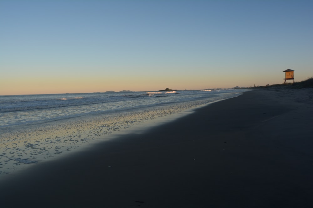 a beach with a light house in the distance