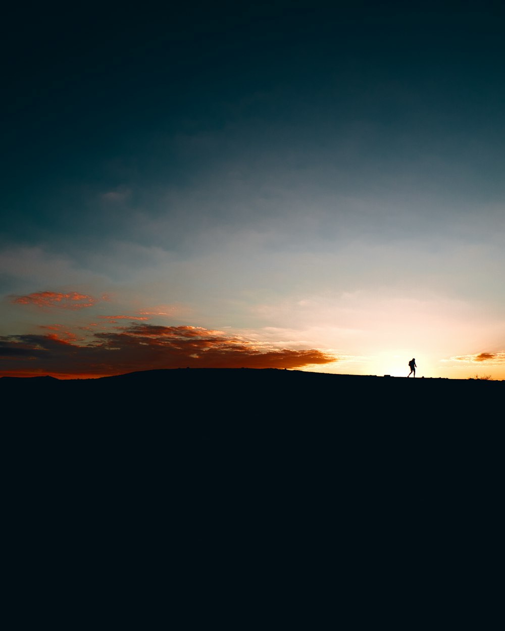 Una persona parada en la cima de una colina al atardecer