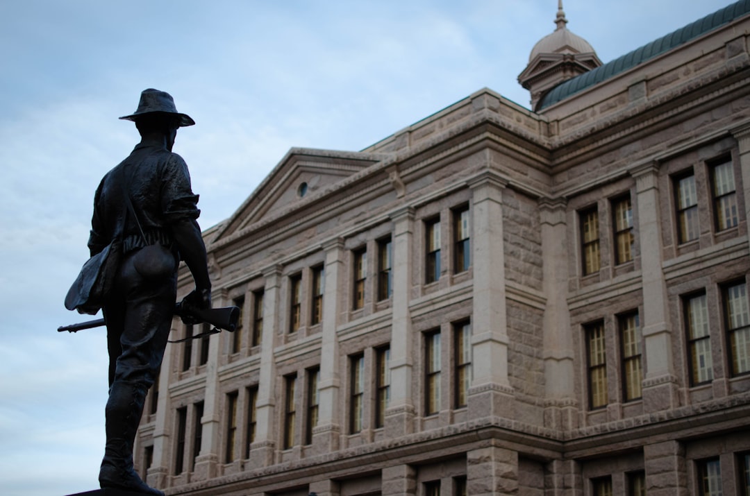 a statue of a man with a gun in front of a building, Statue outside of capital of Texas