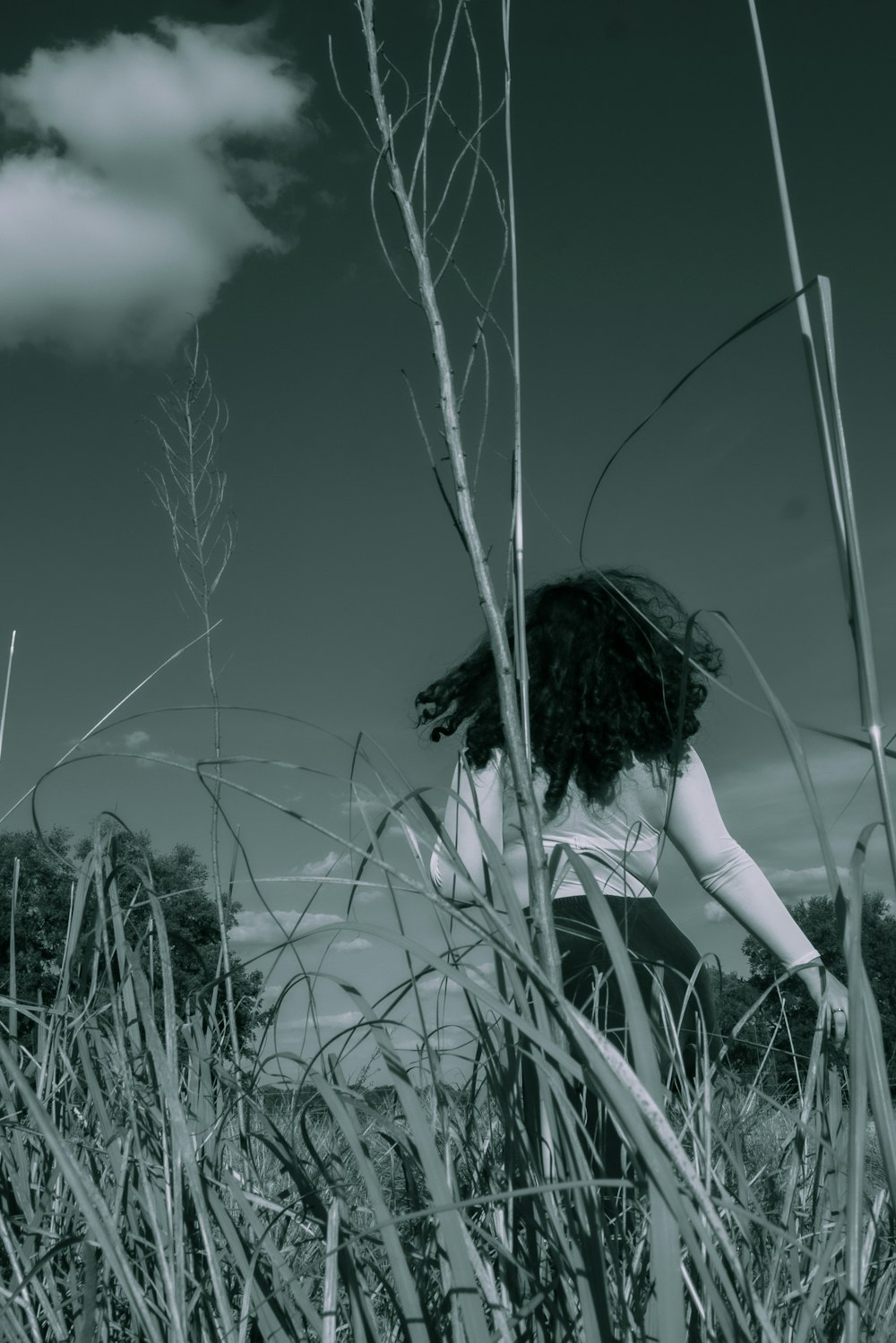 uma mulher em pé em um campo de grama alta