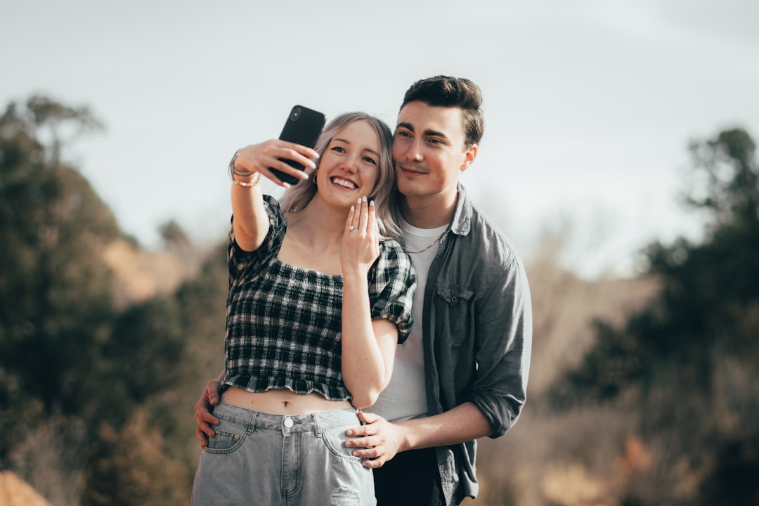 a man taking a picture of a woman with a cell phone, A Newly engaged couple takes a sick selfie