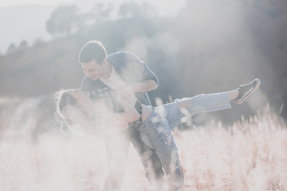 a man holding a woman in a field of tall grass