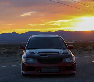 A sleek, modern taxi parked against the backdrop of Uttarakhand’s scenic mountains during sunset.