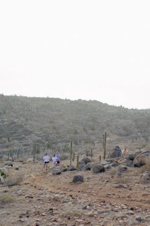 A group of travelers hiking along a rocky ridge with vast Outback landscapes stretching beyond.