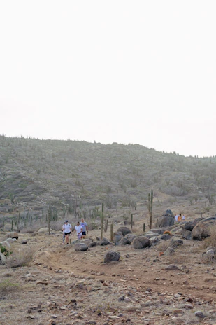 A group of travelers hiking along a rocky ridge with vast Outback landscapes stretching beyond.