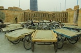 Several three-wheeled carts are arranged in a circular pattern in an open area with stacks of bricks lining the walls. The carts have wooden platforms and are surrounded by an industrial environment, likely used for transporting materials.