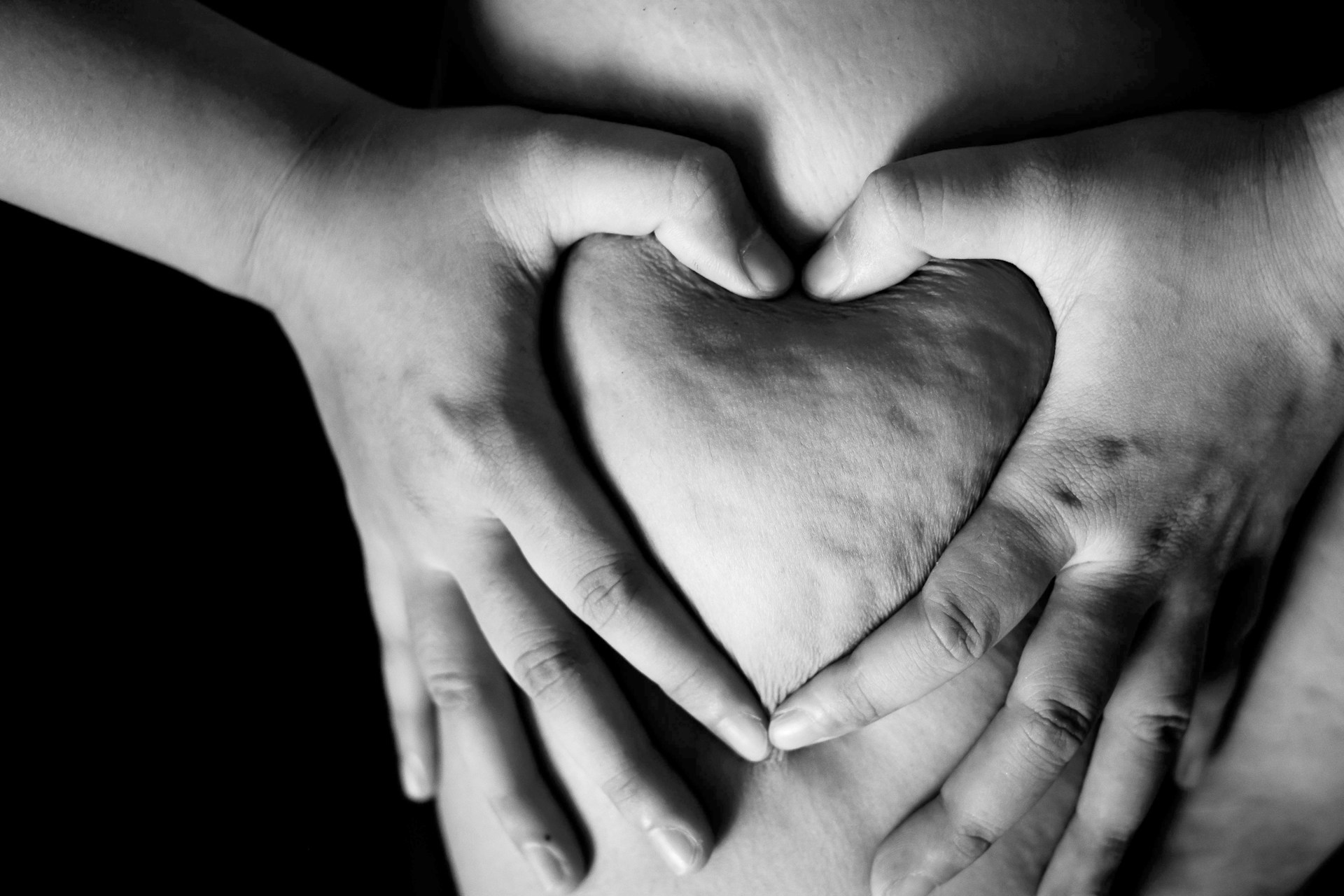 a black and white photo of two hands holding a heart