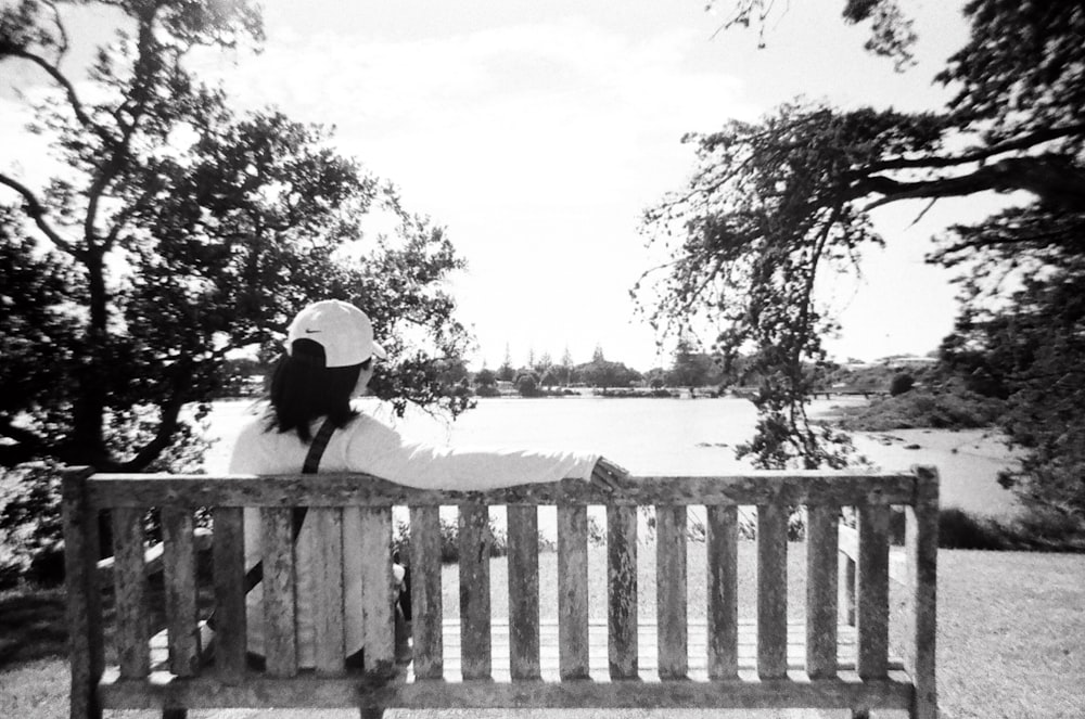 a woman sitting on top of a wooden bench