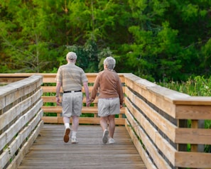 A cheerful senior couple walking hand-in-hand along a tree-lined path.