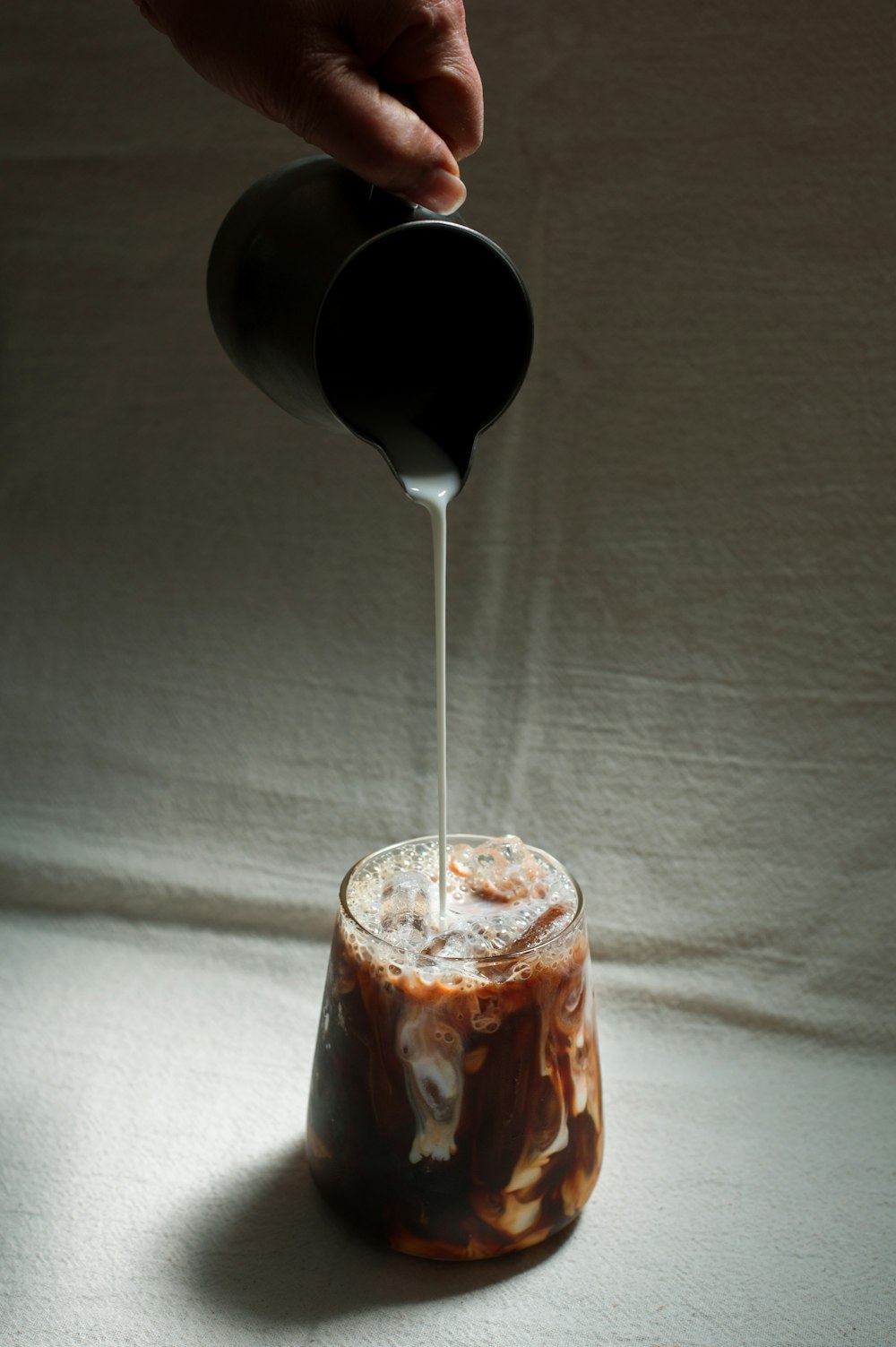 a person pouring something into a glass on a table