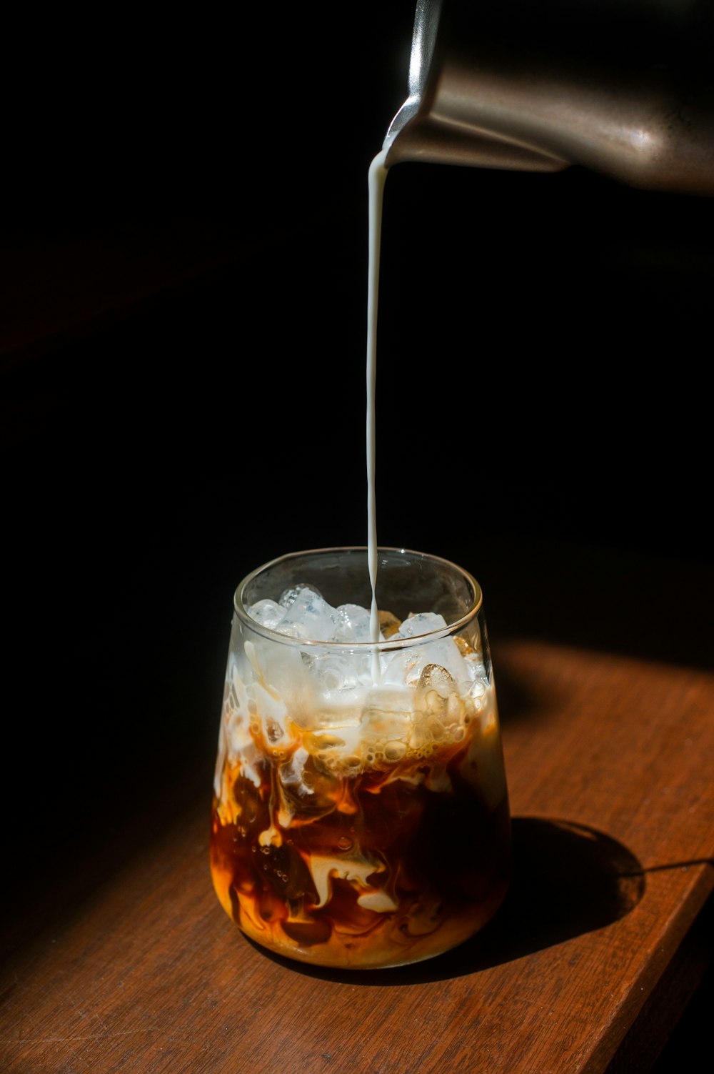 a glass filled with liquid sitting on top of a wooden table