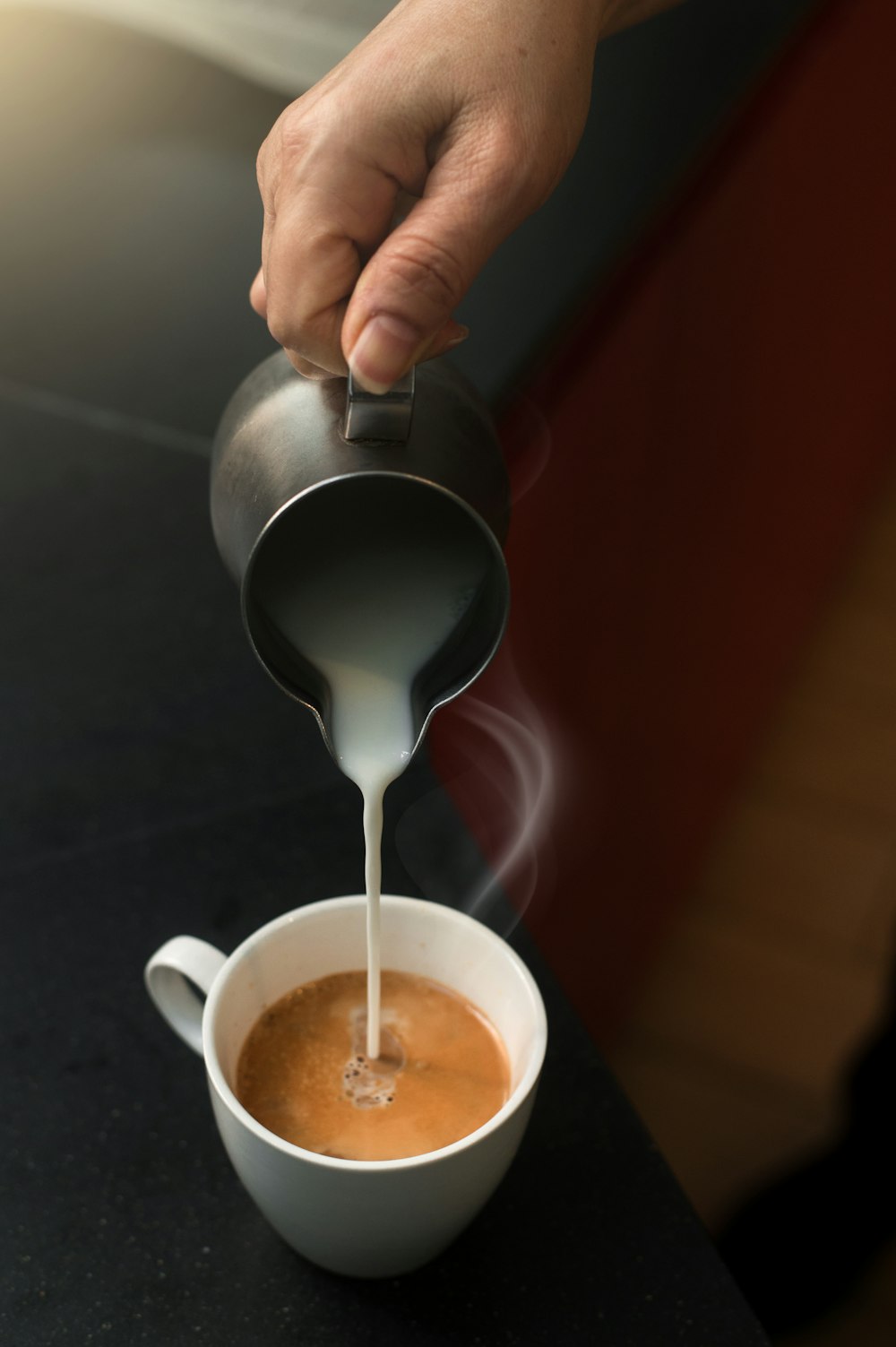 a person pours milk into a cup of coffee