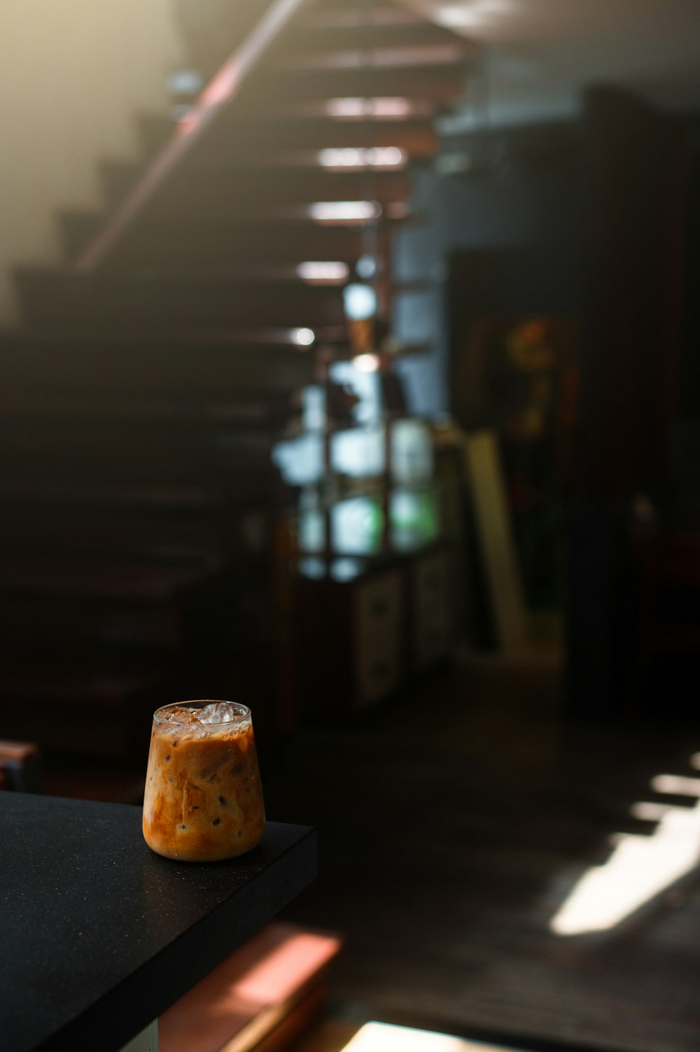 a drink sitting on top of a table next to a stair case