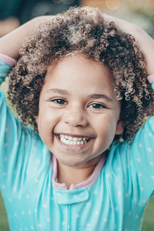 a little girl with curly hair is smiling