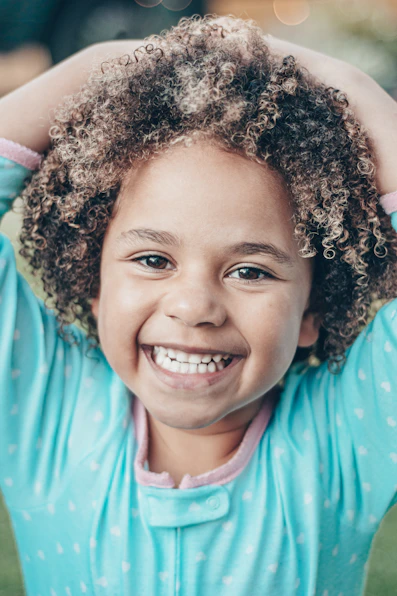 a little girl with curly hair is smiling