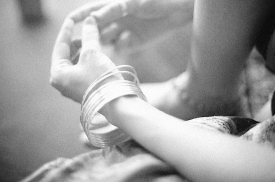 Close-up of hands wearing bright enamel bangles stacked together, glowing under soft natural light.