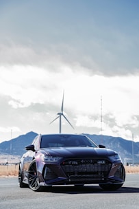 A sleek, modern car parked on a scenic road with mountains in the background.