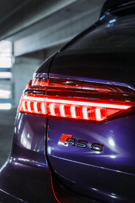 Shiny red and silver custom stoplamp fitted on a modern car tail, illuminated in a stylish garage setting